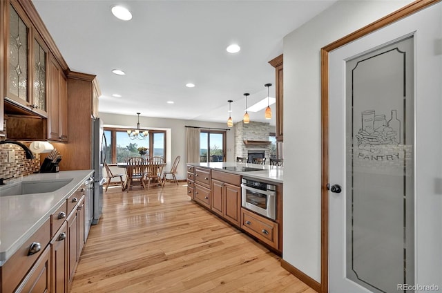 723 Orion Dr, Colorado Springs, CO 80906 - kitchen featuring stainless steel appliances, a sink, light wood-style floors, brown cabinetry, and decorative light fixtures