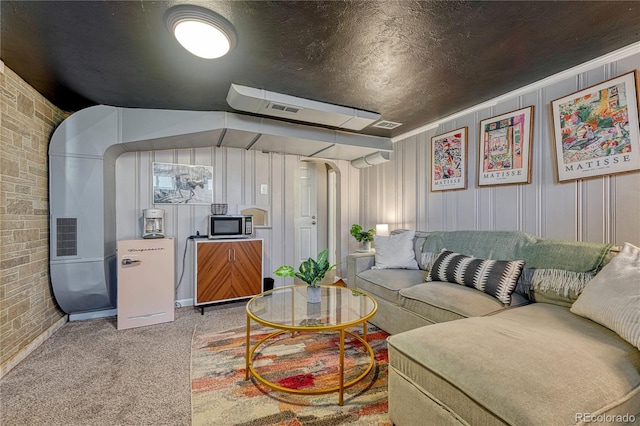 carpeted living room featuring arched walkways, brick wall, and a textured ceiling
