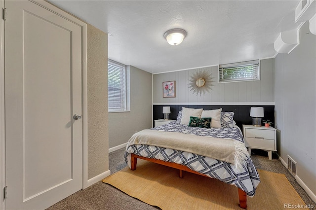 bedroom with carpet, a textured wall, and baseboards