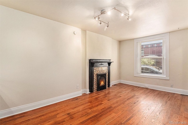 unfurnished living room featuring hardwood / wood-style floors and track lighting