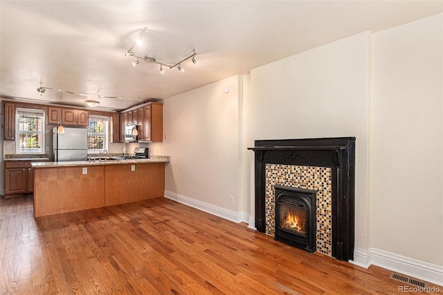 kitchen featuring track lighting, hardwood / wood-style flooring, stainless steel appliances, and kitchen peninsula