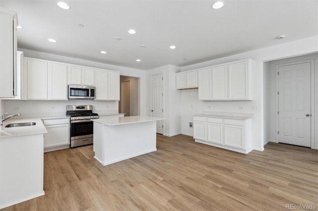 kitchen featuring a kitchen island, appliances with stainless steel finishes, sink, white cabinets, and light wood-type flooring