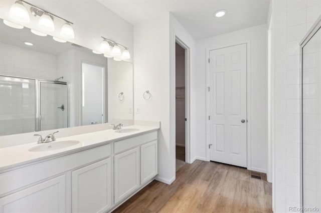 bathroom with walk in shower, wood-type flooring, and vanity