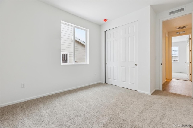 unfurnished bedroom with light colored carpet and a closet