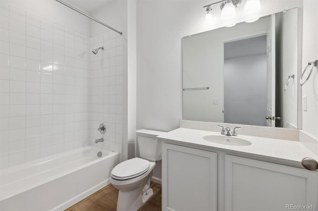 full bathroom with wood-type flooring, toilet, tiled shower / bath combo, and vanity