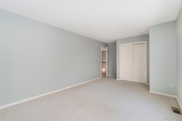 unfurnished bedroom featuring a closet, visible vents, light carpet, and baseboards