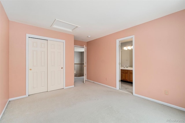 unfurnished bedroom featuring baseboards, a closet, attic access, and light colored carpet