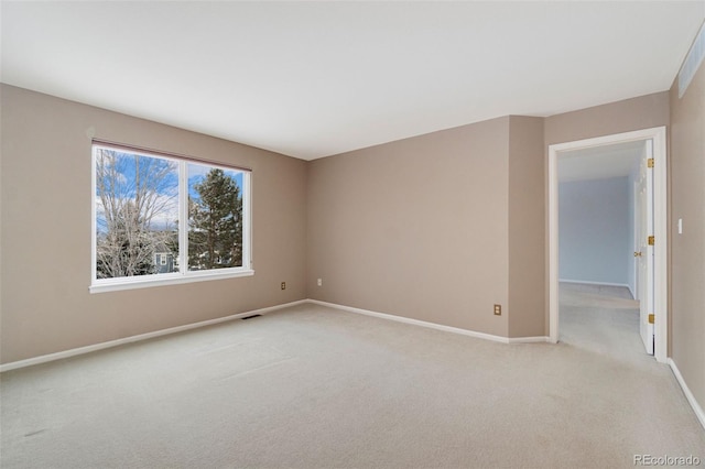 empty room featuring baseboards, visible vents, and light colored carpet