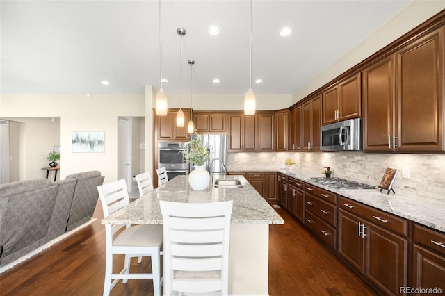 15779 W 83rd Pl, Arvada, CO 80007 - kitchen with stainless steel appliances, a sink, a kitchen bar, light stone countertops, and backsplash