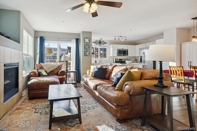 living room with rail lighting, ceiling fan, and a fireplace