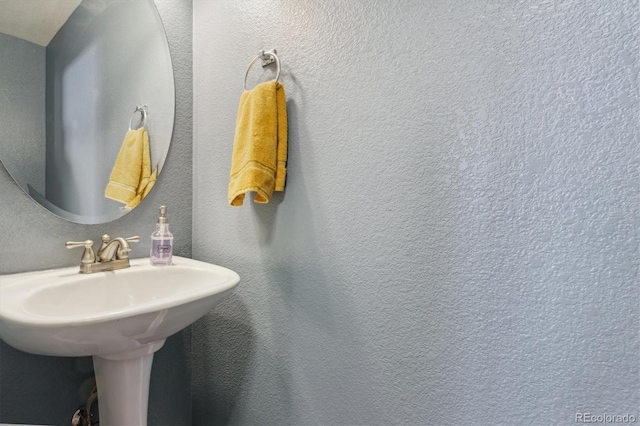 bathroom with a textured wall and a sink