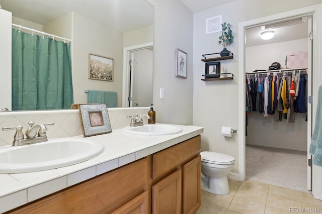 full bath with double vanity, tasteful backsplash, a sink, and tile patterned floors