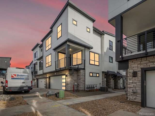 exterior space featuring a garage, cooling unit, stone siding, and driveway