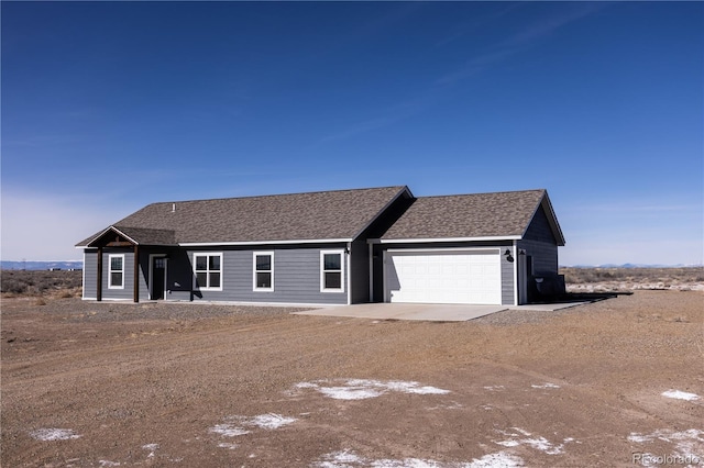 ranch-style home featuring driveway, a shingled roof, and a garage