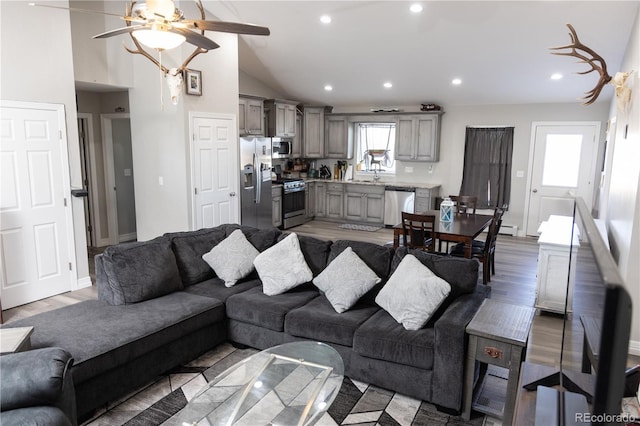 living area with ceiling fan, high vaulted ceiling, light wood-style flooring, recessed lighting, and baseboards