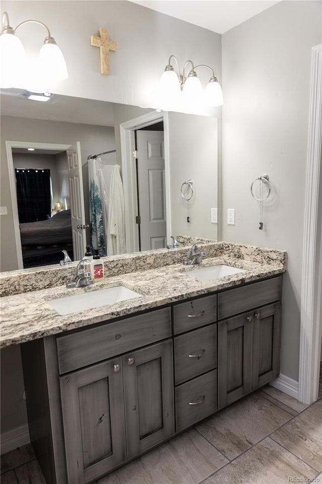 ensuite bathroom featuring ensuite bathroom, double vanity, a sink, and baseboards