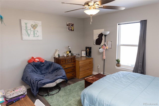 bedroom featuring baseboards, multiple windows, a ceiling fan, and wood finished floors