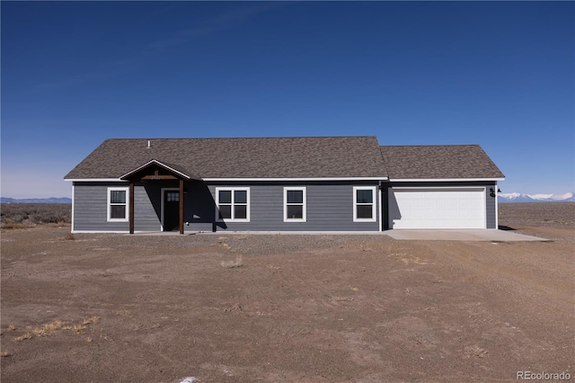 ranch-style home featuring a garage, driveway, and roof with shingles