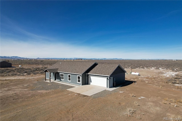 view of front of house featuring a garage, concrete driveway, and roof with shingles