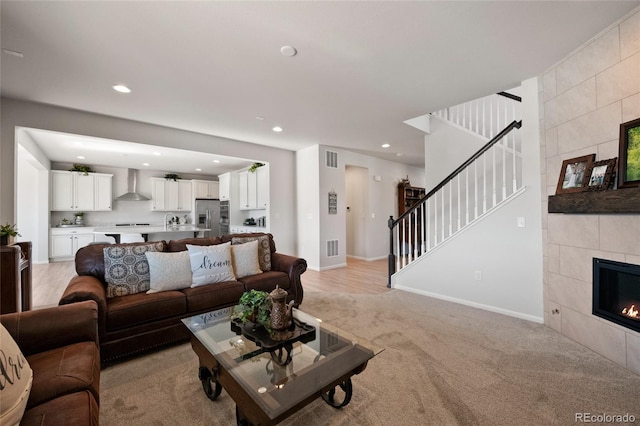 living room featuring light colored carpet, sink, and a tile fireplace