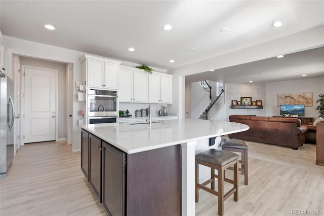 kitchen with appliances with stainless steel finishes, sink, a center island with sink, and white cabinets