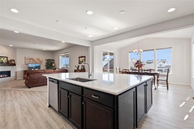 kitchen with a fireplace, dishwasher, sink, hanging light fixtures, and a kitchen island with sink