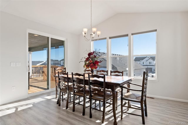 dining area with light hardwood / wood-style floors, vaulted ceiling, and a notable chandelier