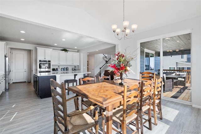 dining area featuring vaulted ceiling, a notable chandelier, and light hardwood / wood-style floors