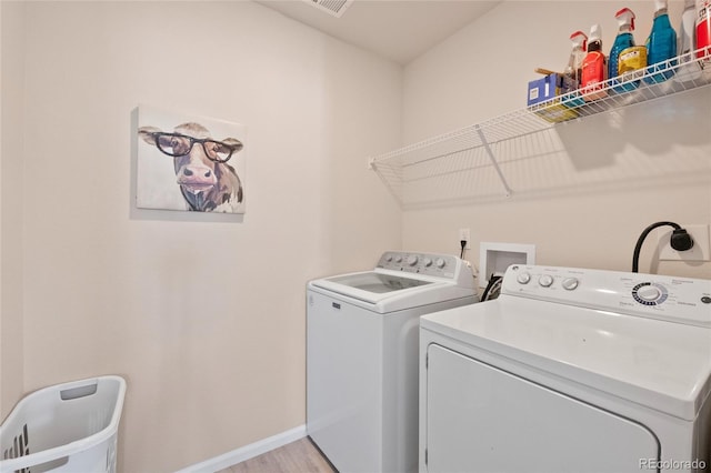 laundry room featuring washer and clothes dryer and light hardwood / wood-style floors