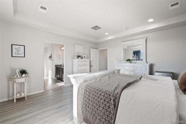 bedroom featuring light hardwood / wood-style flooring and a raised ceiling