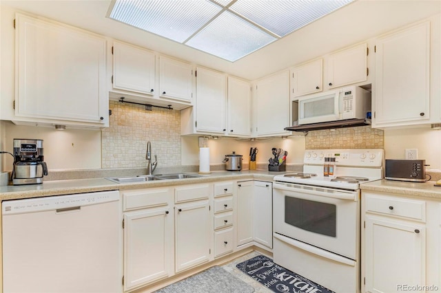 kitchen with tasteful backsplash, white appliances, light countertops, and a sink