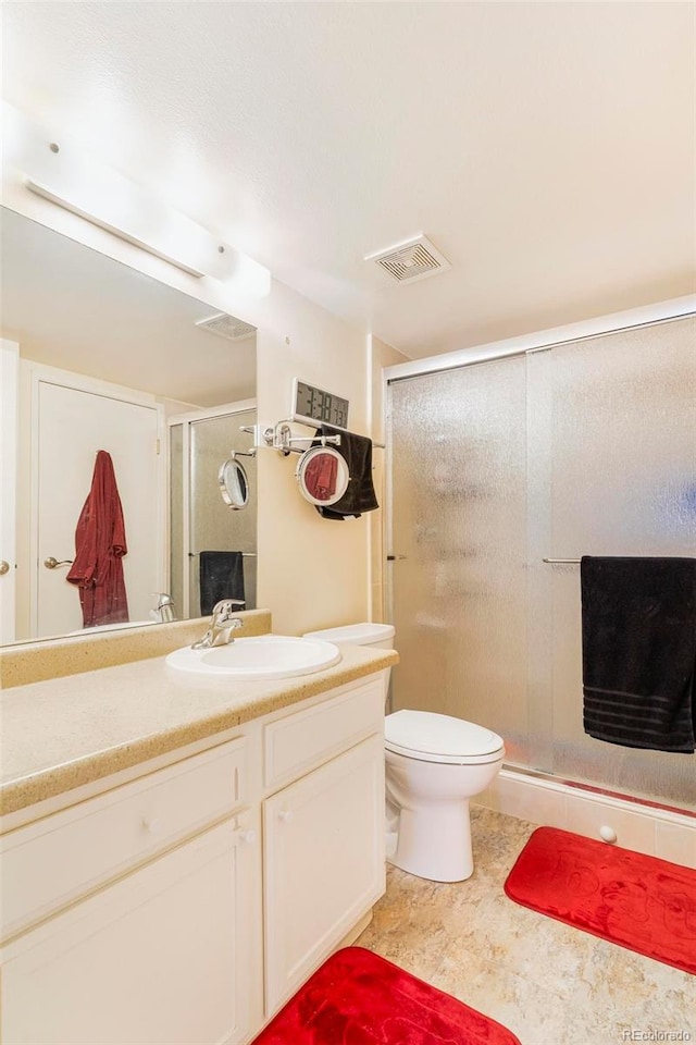 full bathroom featuring toilet, vanity, a shower stall, and visible vents