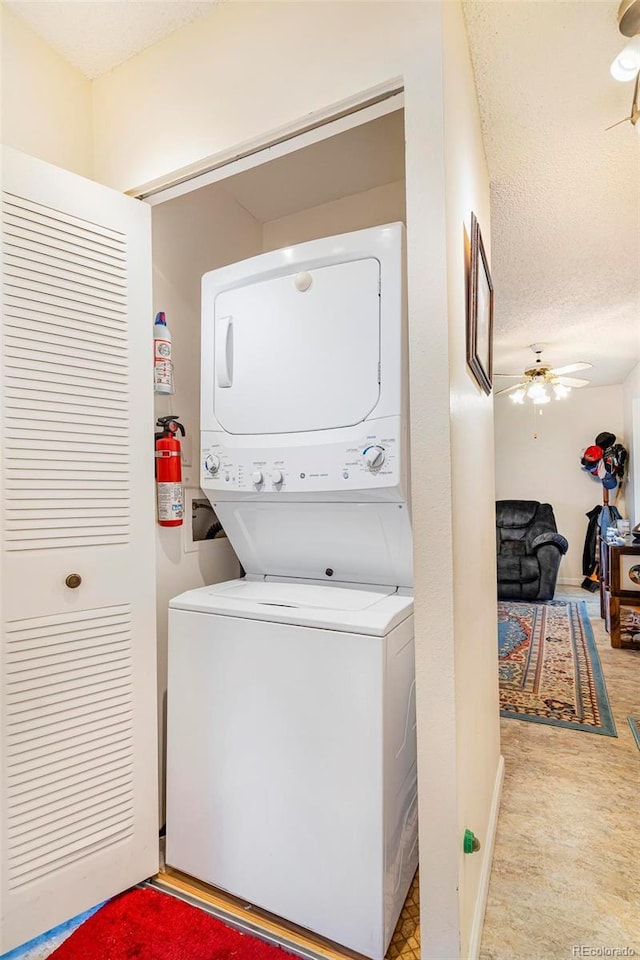 laundry area with a ceiling fan, stacked washer and clothes dryer, a textured ceiling, and laundry area