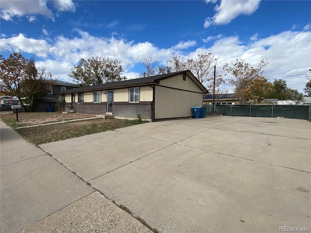 view of side of home with brick siding and fence