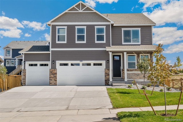 craftsman inspired home featuring driveway, stone siding, and a front yard