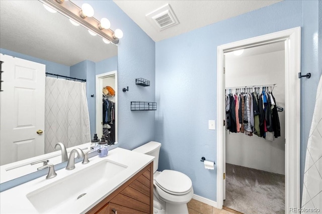 21562 E 47th Ave, Denver, CO 80249 - full bathroom featuring toilet, a walk in closet, visible vents, baseboards, and vanity
