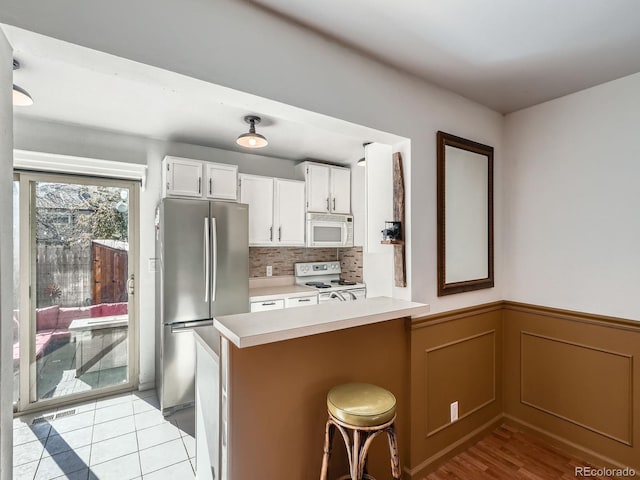 4273 W Ponds Cir, Littleton, CO 80123 - kitchen featuring white appliances, light countertops, tasteful backsplash, white cabinetry, and wainscoting