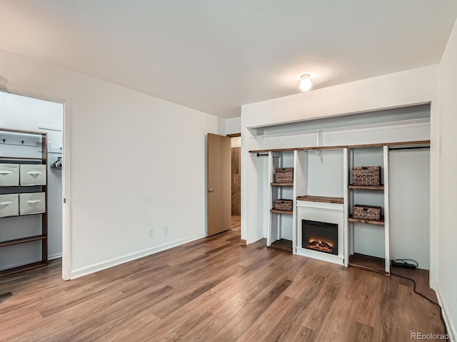4273 W Ponds Cir, Littleton, CO 80123 - unfurnished living room featuring wood finished floors, a warm lit fireplace, and baseboards