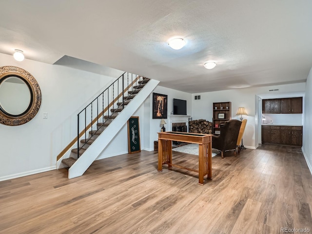 4273 W Ponds Cir, Littleton, CO 80123 - living room with stairs, wood finished floors, a fireplace, baseboards, and a textured ceiling