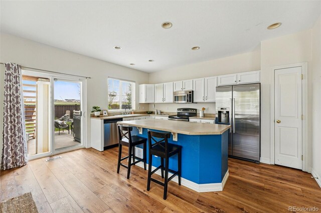 14025 Blue River Trl, Broomfield, CO 80023 - kitchen featuring appliances with stainless steel finishes, light wood-style floors, white cabinets, a center island, and recessed lighting