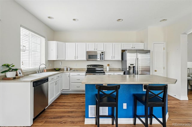 14025 Blue River Trl, Broomfield, CO 80023 - kitchen with stainless steel appliances, a sink, a breakfast bar, white cabinetry, and light countertops