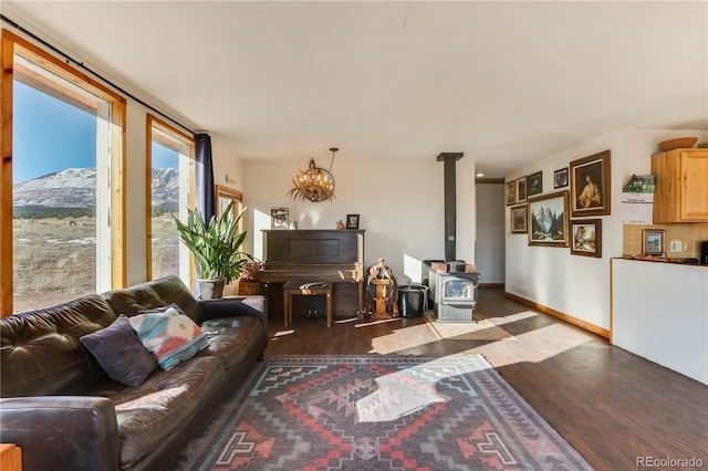 living room with a wood stove, a chandelier, and wood-type flooring