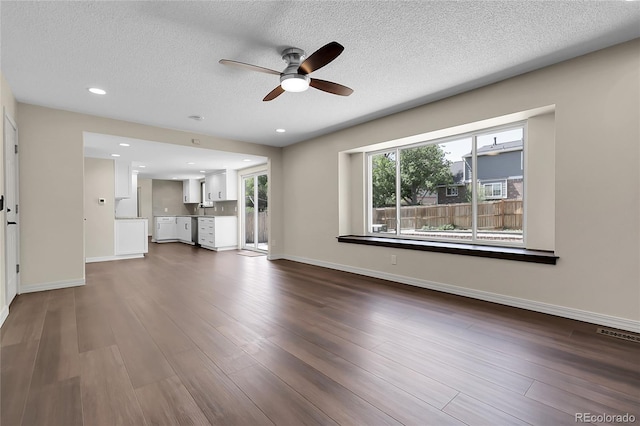 3653 E 133rd Ct, Thornton, CO 80241 - unfurnished living room featuring a ceiling fan, plenty of natural light, dark wood finished floors, a textured ceiling, and baseboards