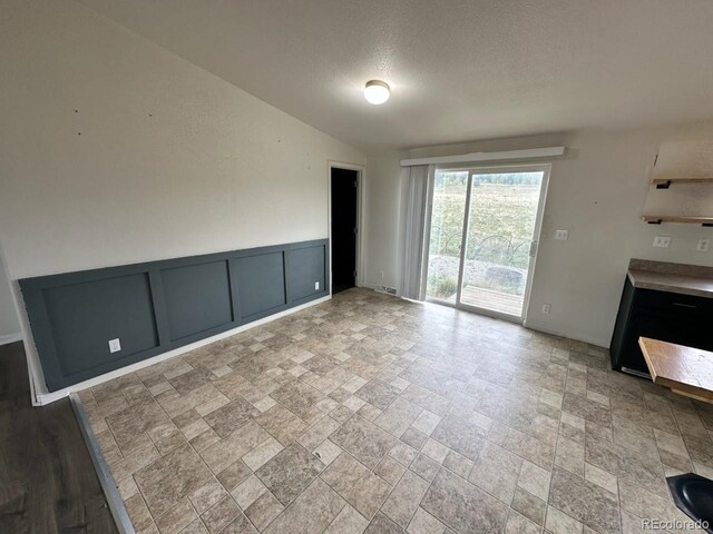 1326 Kaufman Rd, Hartsel, CO 80449 - unfurnished living room featuring stone tile flooring, lofted ceiling, and a textured ceiling
