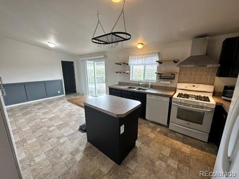 1326 Kaufman Rd, Hartsel, CO 80449 - kitchen with white appliances, wall chimney range hood, a center island, open shelves, and stone finish flooring