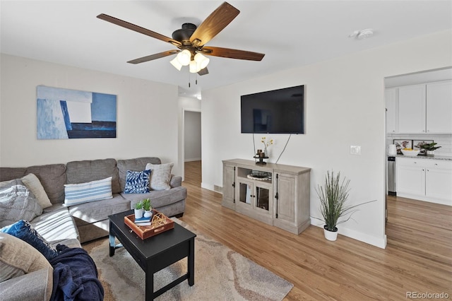 living area with ceiling fan, light wood finished floors, and baseboards