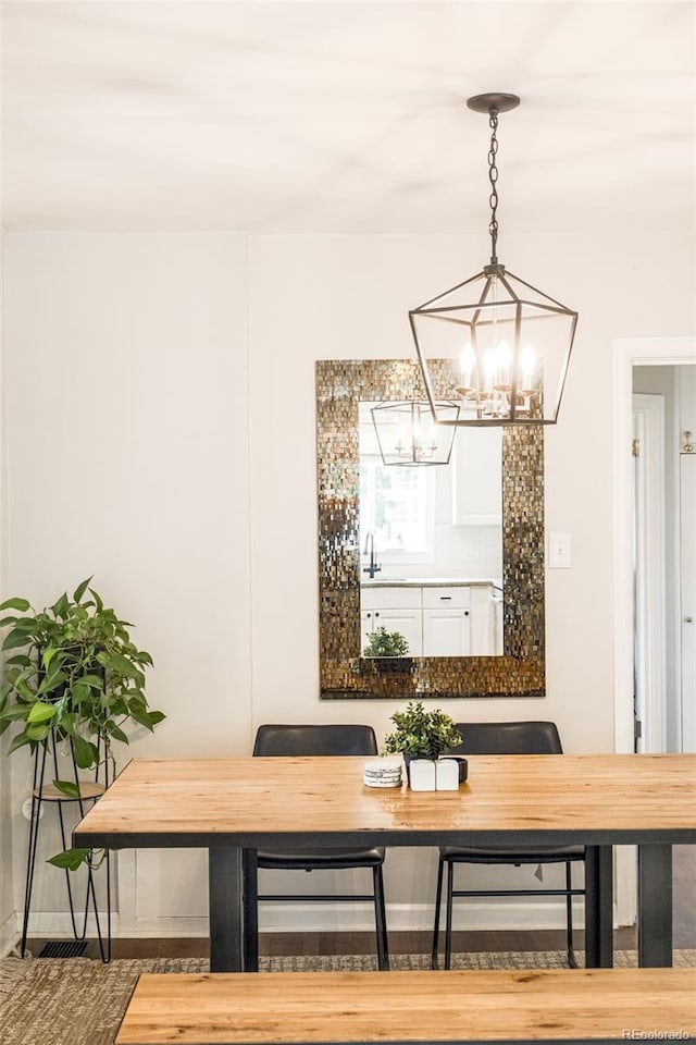 dining space with hardwood / wood-style flooring, a notable chandelier, and sink