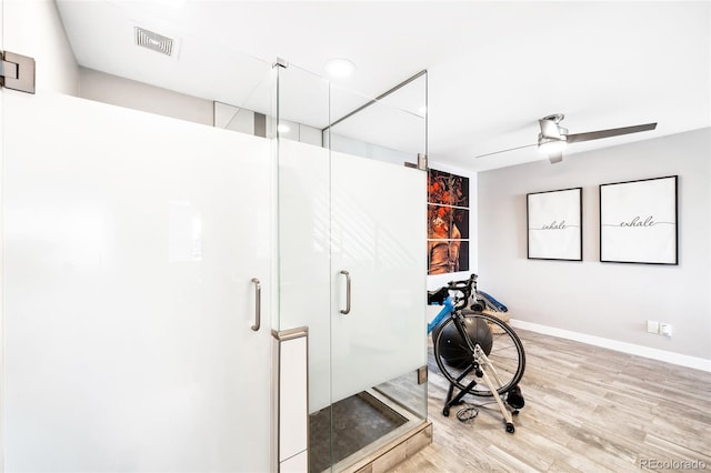 workout area with light wood-style floors, ceiling fan, visible vents, and baseboards