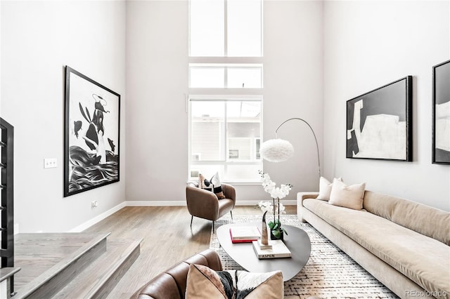 living room with a towering ceiling and light hardwood / wood-style floors