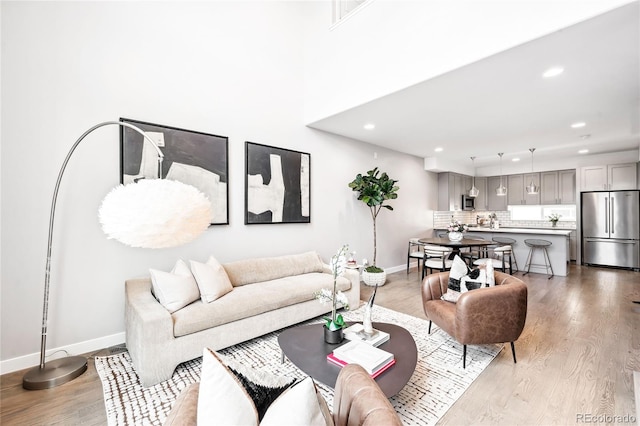 living area featuring recessed lighting, light wood-style flooring, and baseboards